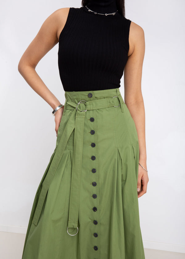 INTERNATIONAL CITIZEN.  Style: Button Skirt. A Button Skirt with box pleats below the hips. Detachable belt with silver ring details for closure. Close up front view. The skirt is made of Italian organic Cotton in Nephrite Jade. Spiritually Infused, Sustainable Luxury Fashion in Berlin.