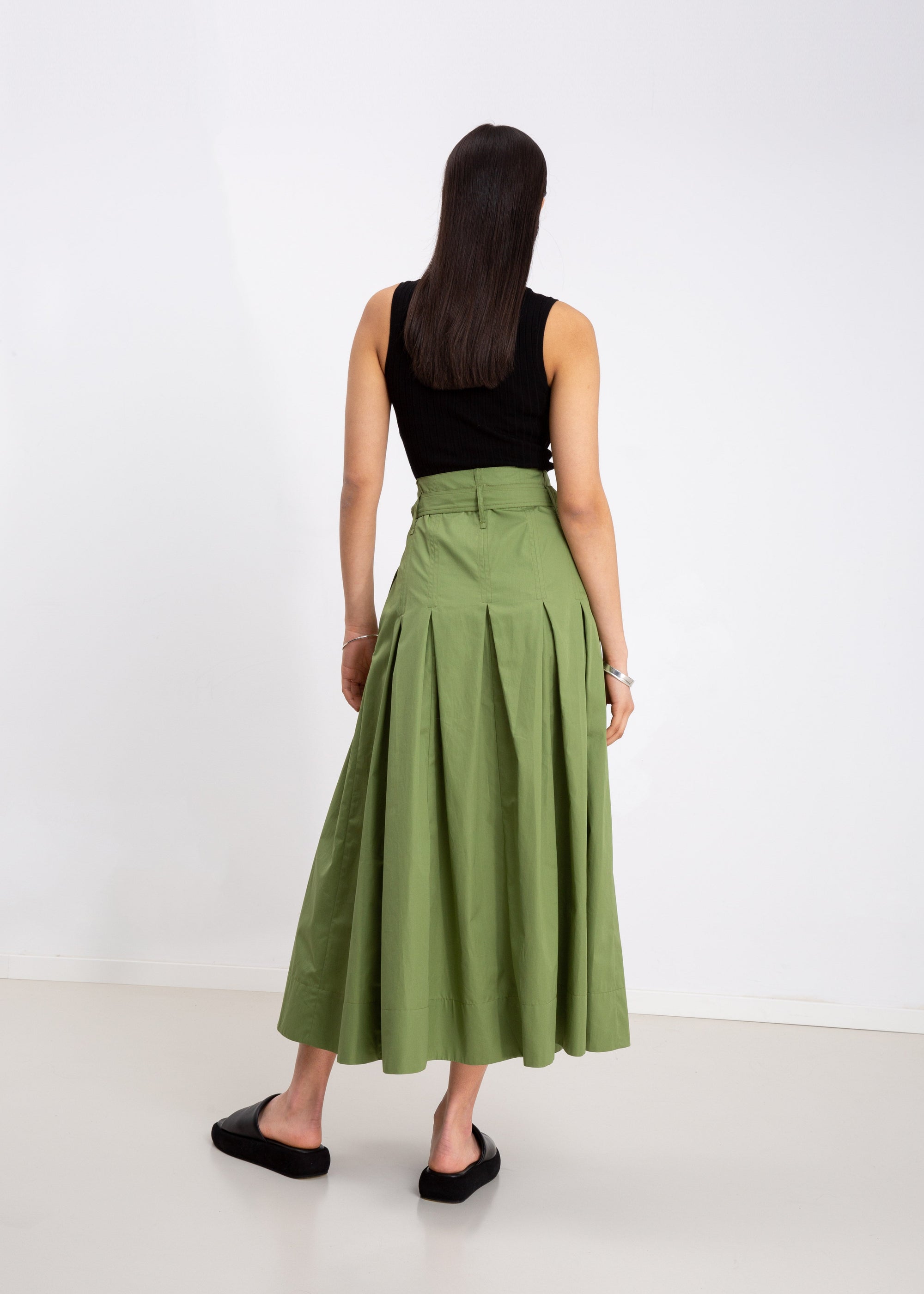INTERNATIONAL CITIZEN.  Style: Button Skirt. A Button Skirt with box pleats below the hips. Back view. The skirt is made of Italian organic Cotton in Nephrite Jade. Spiritually Infused, Sustainable Luxury Fashion in Berlin.