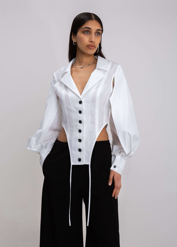 INTERNATIONAL CITIZEN.  Style: A French Cut Button Bodysuit with tie closures. It features exaggerated sleeve volume pleated at the cuffs. Close up front view. Made of Italian Organic Cotton, White Quartz. Spiritually Infused, Sustainable Luxury Fashion in Berlin.
