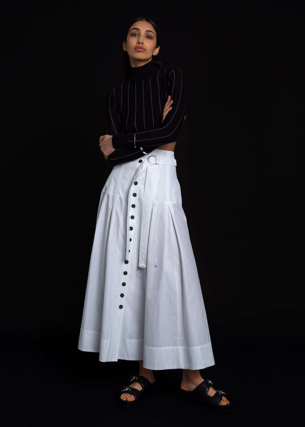 INTERNATIONAL CITIZEN.  Style: Button Skirt.  A Button Skirt with box pleats below the hips. Detachable belt with silver ring details for closure. The skirt is made of Italian organic Cotton in White Quartz. Spiritually Infused, Sustainable Luxury Fashion in Berlin.