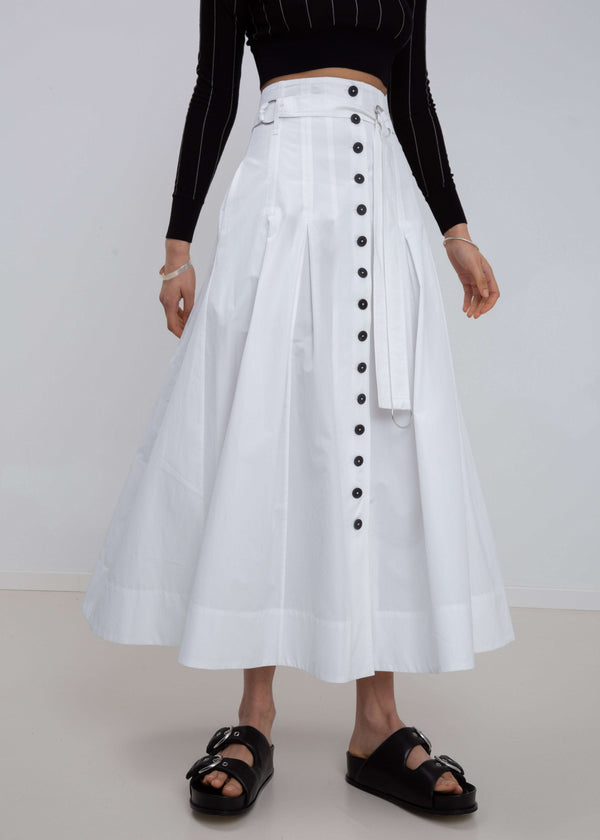 INTERNATIONAL CITIZEN.  Style: Button Skirt. Close up front view #2. A Button Skirt with box pleats below the hips. Detachable belt with silver ring details for closure. The skirt is made of Italian organic Cotton in White Quartz. Spiritually Infused, Sustainable Luxury Fashion in Berlin.