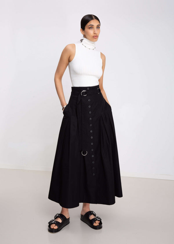 INTERNATIONAL CITIZEN.  Style: Button Skirt. Close up front view. A Button Skirt with box pleats below the hips. The skirt is made of Italian organic Cotton in Obsidian Black. Spiritually Infused, Sustainable Luxury Fashion in Berlin.