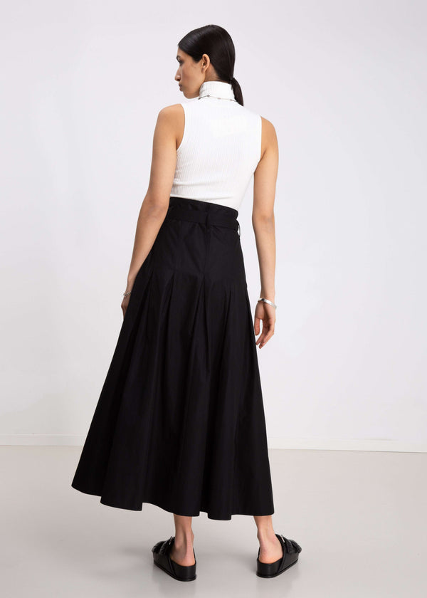 INTERNATIONAL CITIZEN.  Style: Button Skirt. Back view. A Button Skirt with box pleats below the hips. Detachable belt with silver ring details for closure. The skirt is made of Italian organic Cotton in Obsidian Black. Spiritually Infused, Sustainable Luxury Fashion in Berlin.
