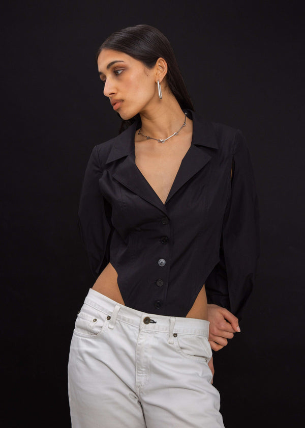 INTERNATIONAL CITIZEN.  Style: A French Cut Button Bodysuit with tie closures. Front view worn into pants. Made of Italian Organic Cotton, Obsidian Black. Spiritually Infused, Sustainable Luxury Fashion in Berlin.