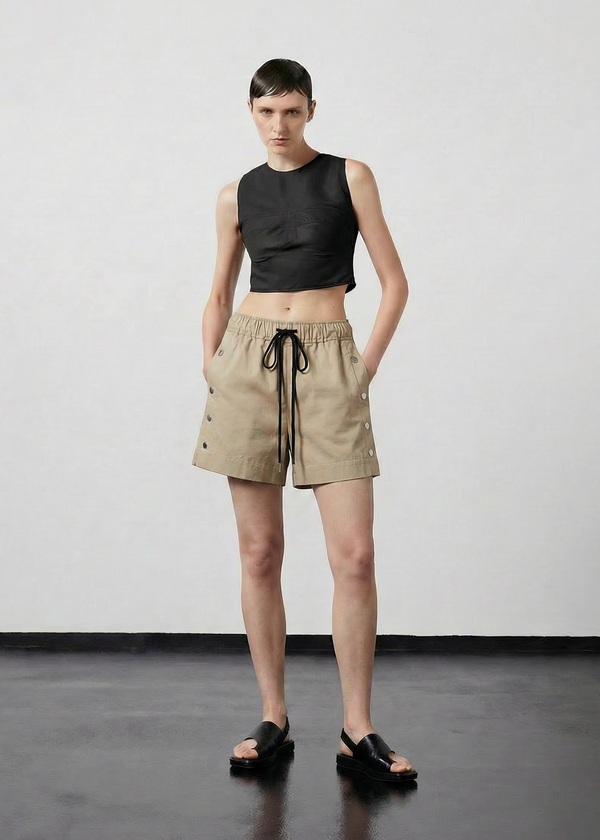 INTERNATIONAL CITIZEN.  Style: The Track Short has a smooth back waistband and elastic front with a drawcord tunnel at the front. Silver metal snaps down the side and mid thigh length. Unisex item. Made of Italian Organic Cotton Twill, Dune. Spiritually Infused, Sustainable Luxury Fashion in Berlin.