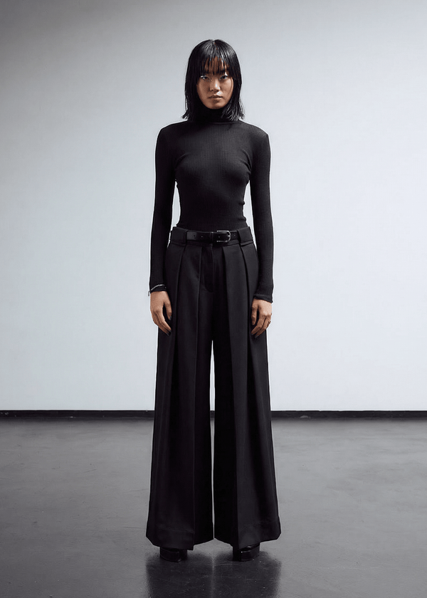 INTERNATIONAL CITIZEN.  Style: The Deep Pleated Pant, falls below the natural waist. The pleats nearly meet at the center front and at the center back. Made of Italian RWS Wool, Obsidian Black Purple. Spiritually Infused, Sustainable Luxury Fashion in Berlin.