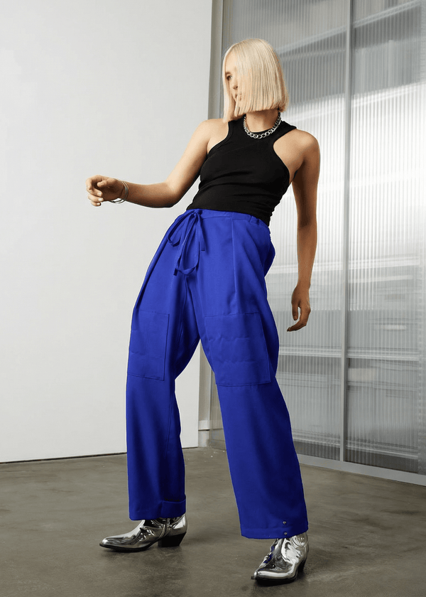 INTERNATIONAL CITIZEN.  Style: The JiuJitsu Pants are have a drawstring closer at the waist, a straight leg with silver snap hem straps and a thigh patch. Unisex item. Made of Italian Wool, certified (RWS) Responsible Wool Standard, Lapis Lazuli Blue. Spiritually Infused, Sustainable Luxury Fashion in Berlin.