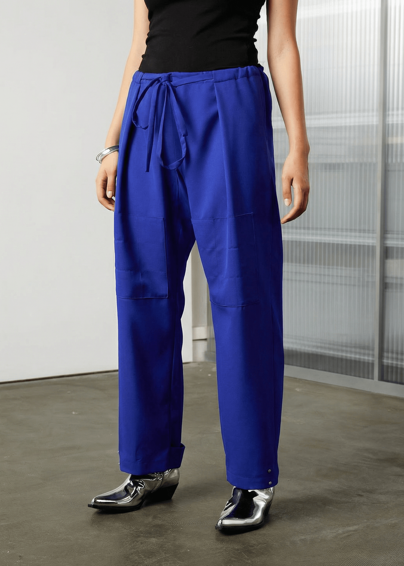 INTERNATIONAL CITIZEN.  Style: The JiuJitsu Pants are have a drawstring closer at the waist,  a straight leg with silver snap hem straps and a thigh patch. Unisex item. Front pant view. Made of Italian Wool, certified (RWS) Responsible Wool Standard, Lapis Lazuli Blue. Spiritually Infused, Sustainable Luxury Fashion in Berlin.